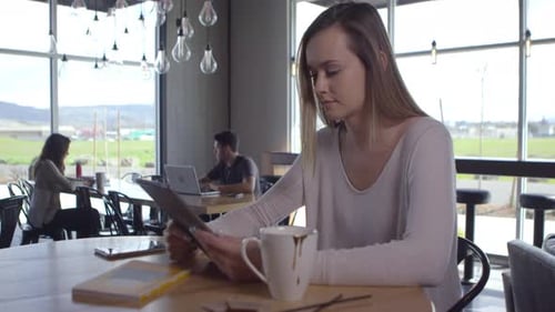 Woman Using Tablet at Cafe with Natural Light