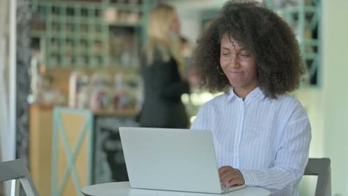 Professional African Businesswoman Doing Video Call on Laptop in Cafe