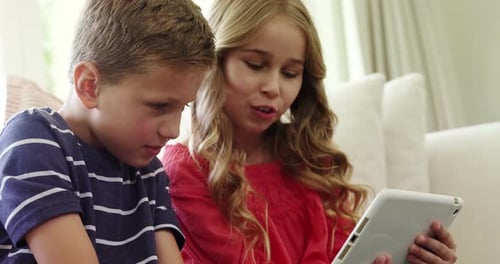 Children Using Tablet Together on Couch Indoors