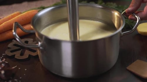 Le cuisinier utilise un mixeur plongeant pour faire de la purée de soupe dans la poêle en métal, cuire des aliments sains, de la purée