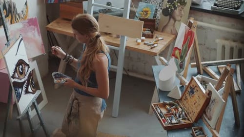 Young Woman Painting Eyes on Canvas in Art Studio