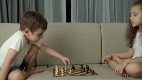Children Play Chess While Sitting on the Devan at Home the Development of Logical Thinking in