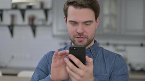 Man Celebrates Using Phone in Modern Kitchen