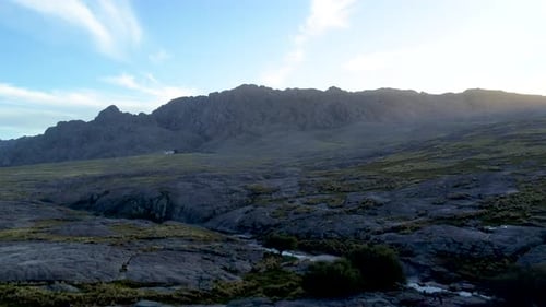 Drone flight over a mountain of rocks during sunset.