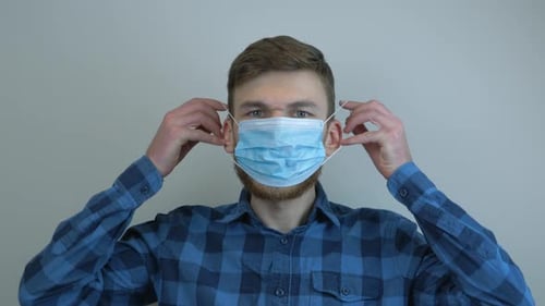 Young Adult Putting On a Surgical Mask