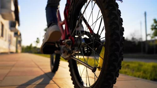 Person Riding Bicycle on Sidewalk in Neighborhood