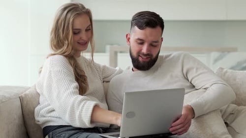 Happy Couple on Couch Using Laptop