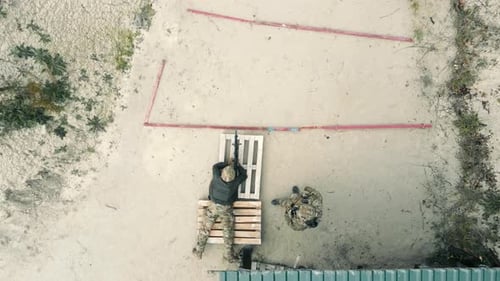 Aerial Top View of a Sniper Aiming at a Target with an Assistant