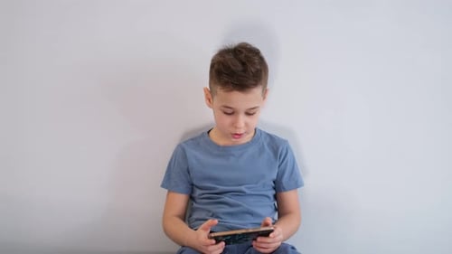 Young Boy Using Mobile Phone in Bright Room