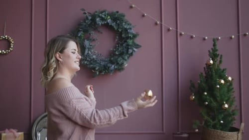Woman Tossing Christmas Ornament in Decorated Home