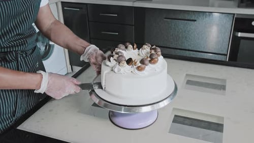 Slicing a Layered Birthday Cake with White Icing