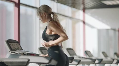 Fit Girl Training Cardio Exercise on Running Machine in Fitness Center