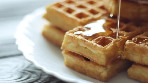 Golden Syrup Pouring Over Waffles on White Plate