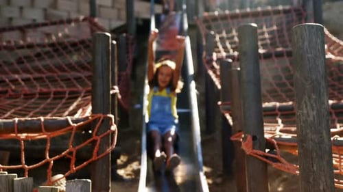 Schoolgirl sliding on slide in school playground