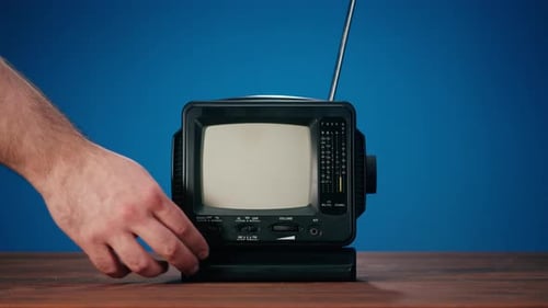 Hand Turns on a Vintage Television with Static