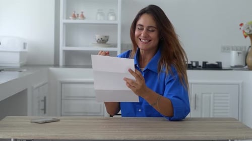 Woman Excited by Document in Bright Kitchen