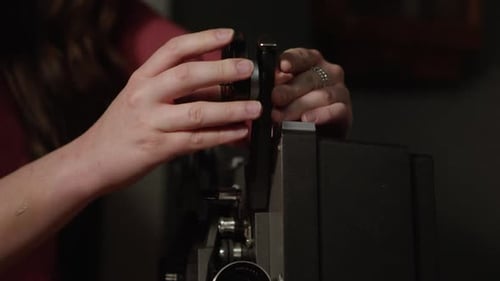 Person putting film reel on old projector