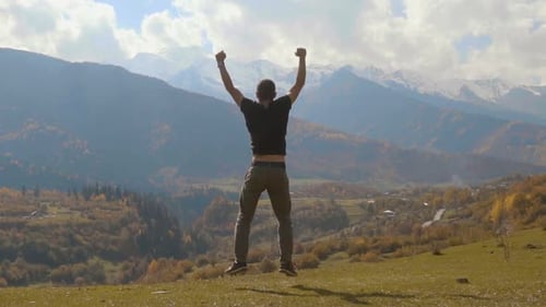 Mann springt und klatscht mit den Händen vor dem Hintergrund der herbstlichen Berge.