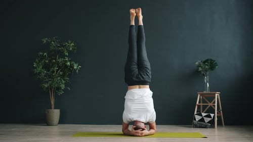 Zeitlupe eines fortgeschrittenen Yoga-Schülers beim Kopfstandtraining im Studio