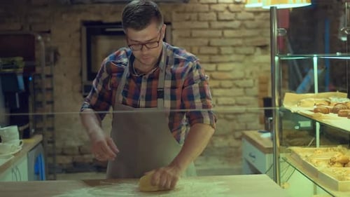 A Exhausted Male Baker Is Kneading Dough,making Bread with a Rolling Pin and Wipes Sweat From His