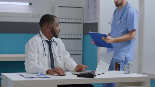 Doctors Collaborate Over Laptop in Bright Office