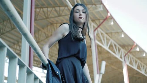 Stylish Woman Leaning Against Railing in Urban Setting