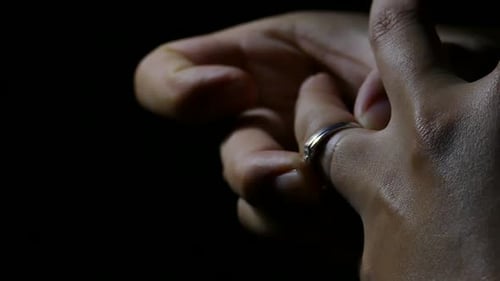 Hand Removes Silver Ring in Dark Close Up