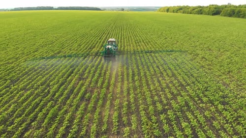 Aerial View of Farming Tractor Spraying on Field with Sprayer Herbicides and Pesticides at Sunset