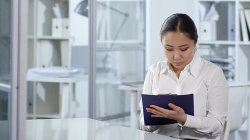 Asian Woman Observing Invisible AR Object and Writing on Clipboard
