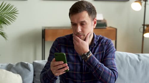 Man Using Cell Phone in Living Room at Home
