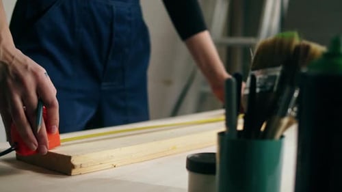 Woman Builder Using Roulette Wheel and Drawing Mark on Wooden Board Closeup
