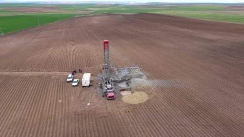 Bohranlage arbeitet auf flachem landwirtschaftlichem braunem Feld