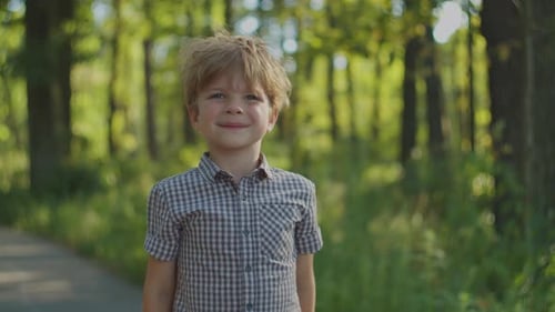 Smiling Boy Standing in a Green Forest