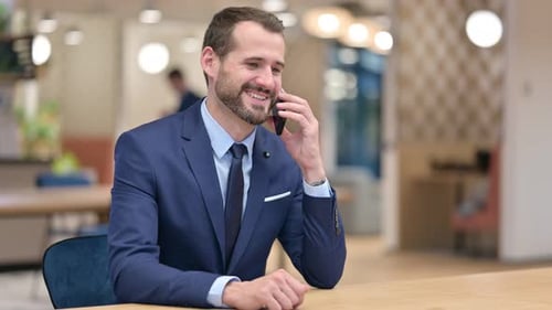Cheerful Businessman Talking on Smartphone in Office