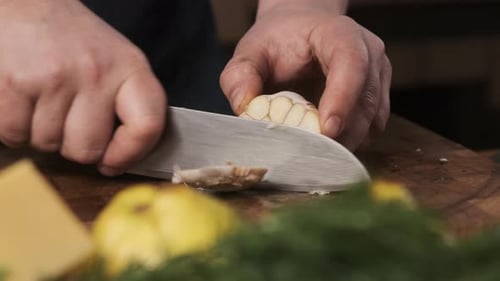 Chef in Restaurant Kitchen Cuts Garlic with Sharp Shiny Knife
