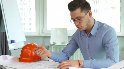 Architect Reviewing Building Plans at Desk