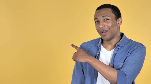 Man Pointing to the Left on Yellow Background