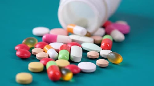 Close Up of Colorful Pills Spilling on Green Background