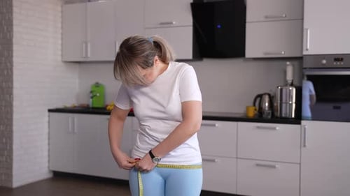Mulher que está perdendo peso fazendo medições na cozinha