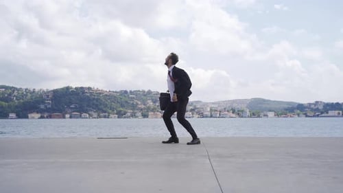 Man in Suit Jumps for Joy on Pier