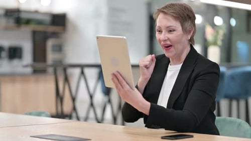 Excited Woman Celebrates Success Using Tablet at Work