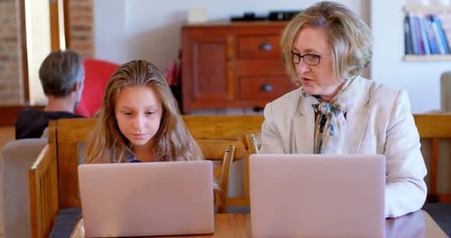 Girl Learning on Laptop with Assistance from Woman