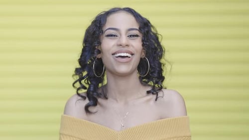 Cheerful Woman Smiles in Front of Yellow Background
