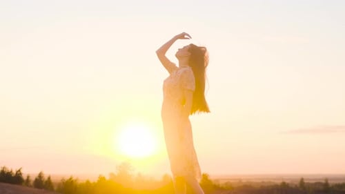 Schlanke sexy Model-Frau in weißem, langem Kleid, glattes Haar und steht auf dem Gipfel oder Rand eines Berges
