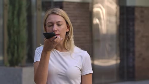 Woman Using Voice Command on Smartphone Outdoors