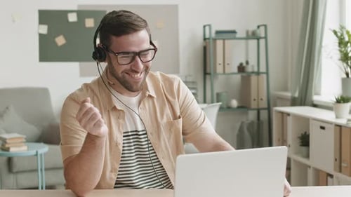 Man Smiling Wearing Headset Talking on Laptop