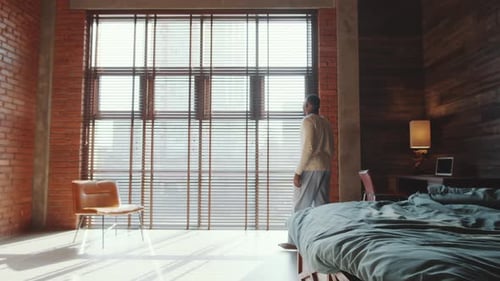 Man Stretching in Sun-Drenched Modern Bedroom