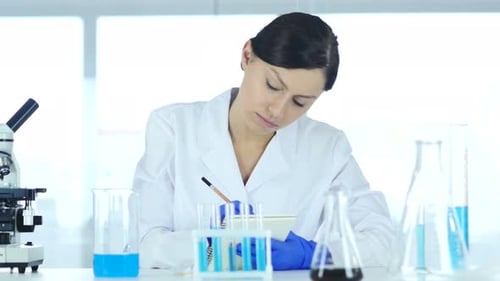 Woman Working with Microscope in Bright Laboratory