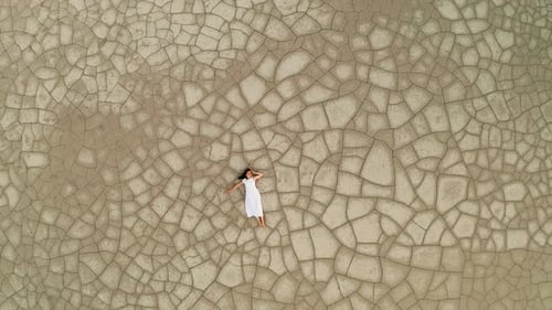 Aerial View of a Woman Lying on the Cracked Ground
