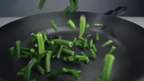 Französische Bohnen fallen in Zeitlupe in die Pfanne, frisches Gemüse fällt in 240 Fps, Kochen